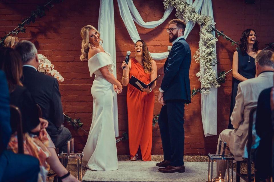 A bride and groom standing at the altar with the celebrant reading their wedding vows