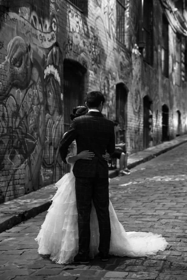 Black and white image of bride and groom embracing in Melbourne laneway full of graffiti street art