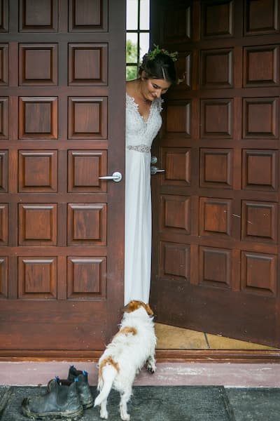Bride opening large wooden door with small terrier peeking inside (1)