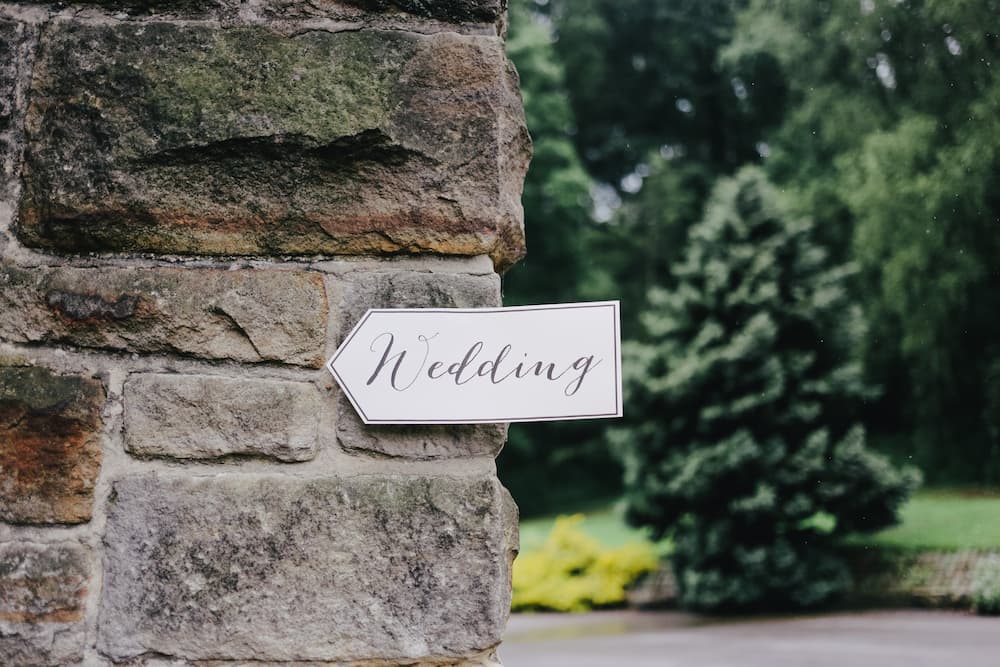 Stone wall at wedding venue with sign reading 'wedding'